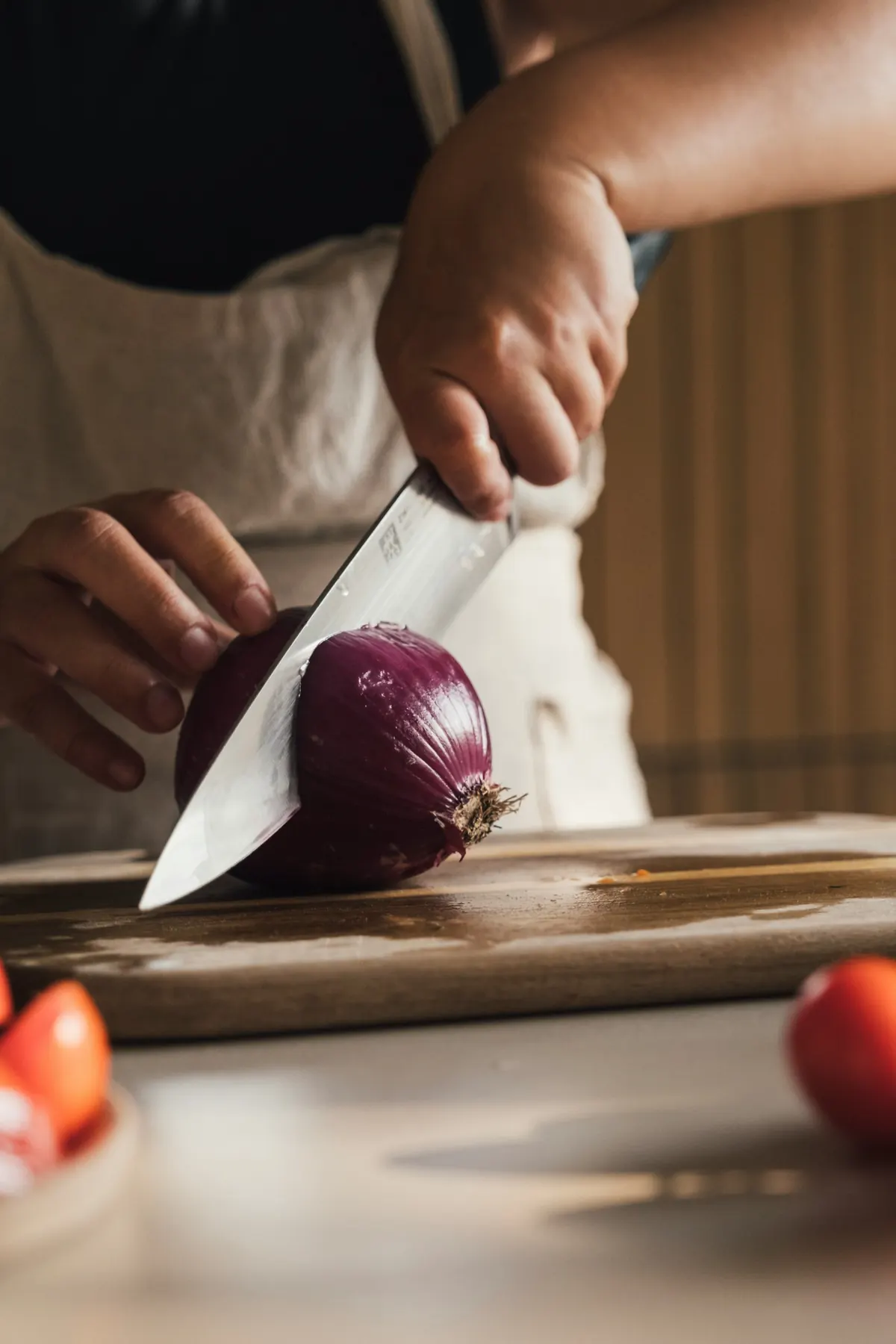 Manos cortando una cebolla morada con luz cálida